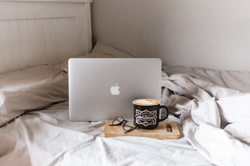 laptop and coffee on a bed